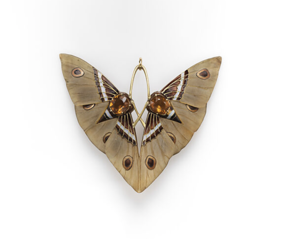 Un pendentif papillon en émail avec ailes dorées et accents marron foncé. Le corps du papillon est un contour doré.